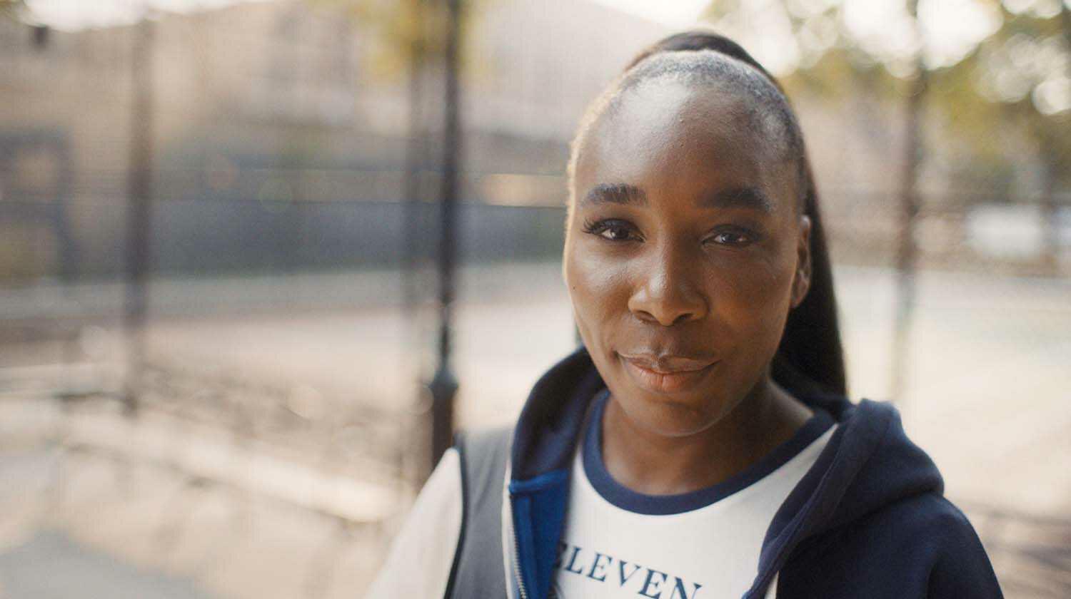 Venus Williams at an outdoor tennis court looking right into camera.