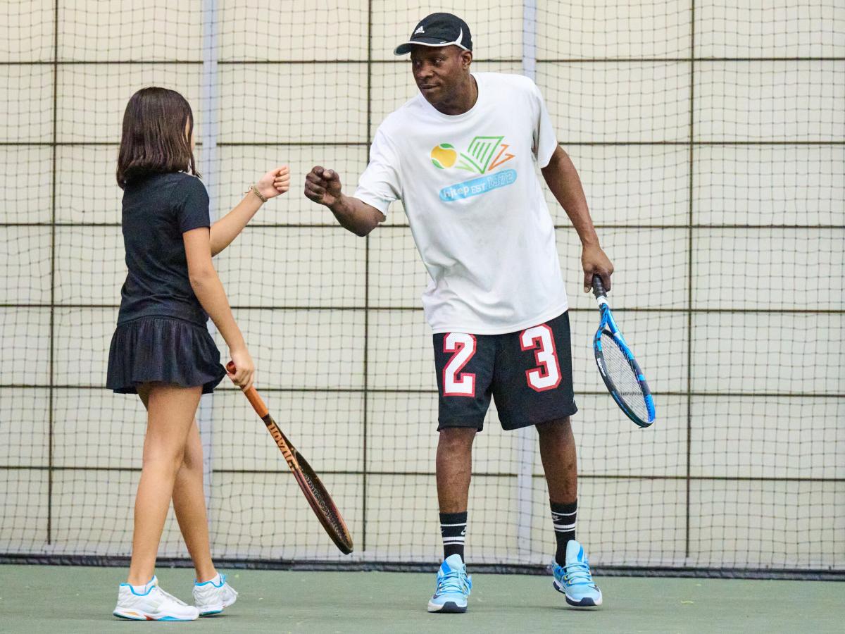 Coach fist-bumping female student on-court during practice at the Armory