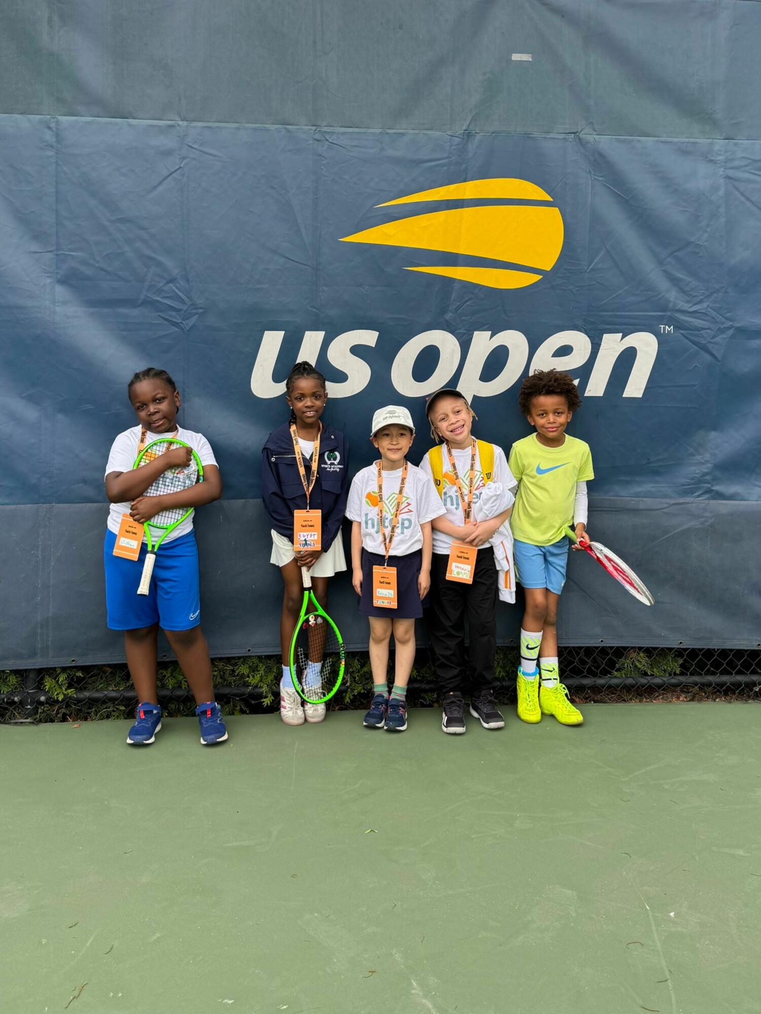 Group of young kids with HJTEP t-shirts at event.